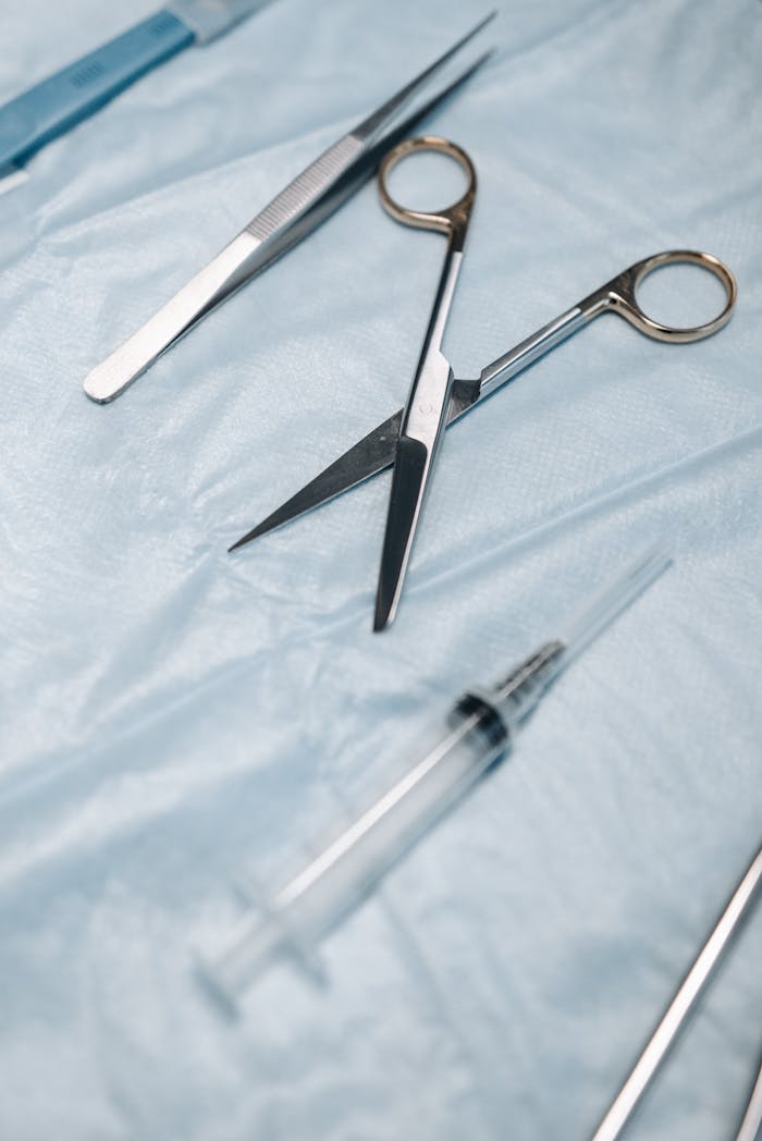 gallery-02 Close-up of surgical scissors, tweezers, and syringe on sterile drapes.